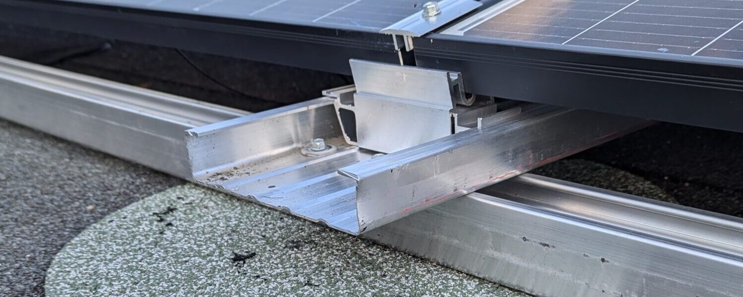 Nahaufnahme der Schienenverbindung unter einem Solarmodul auf einem Flachdach