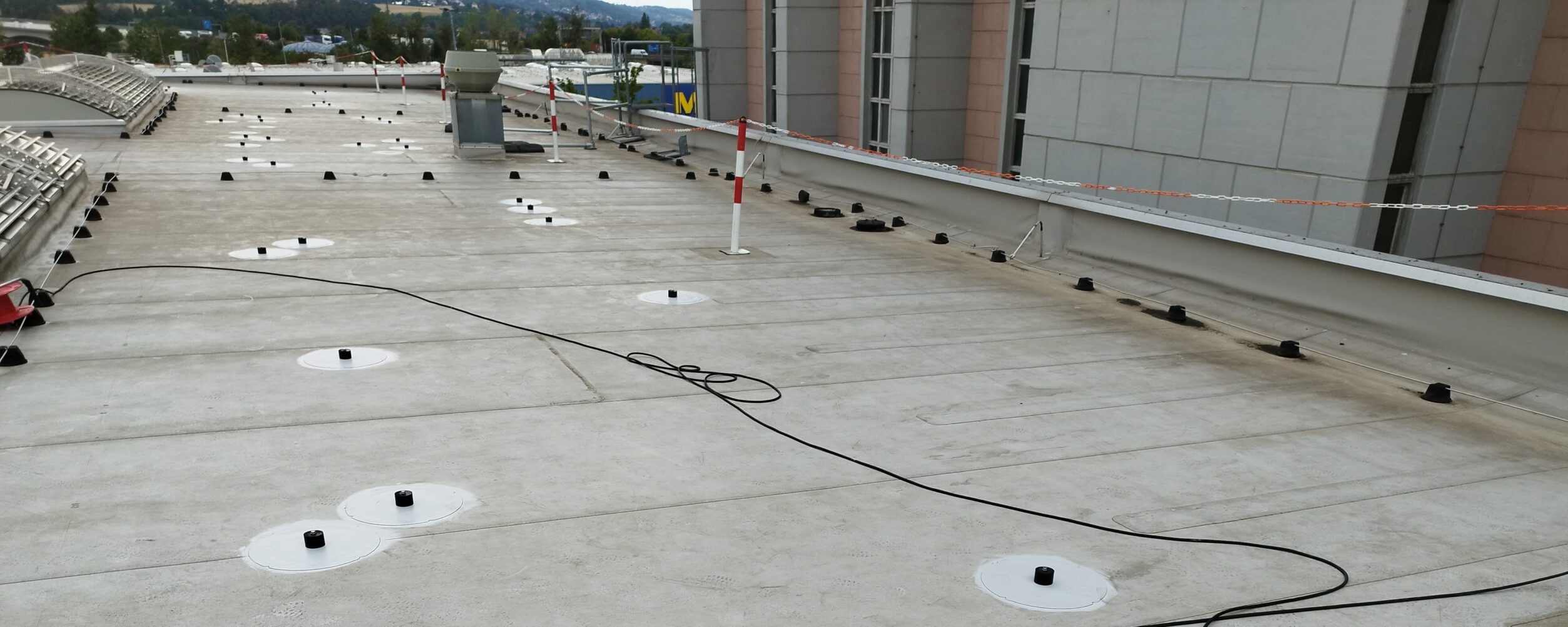 Großflächiges Gewerbedach mit verteilten weißen Befestigungspunkten und ausgelegten Anschlussleitungen
Planung-web montageplan-pv-dachhalter.webp Bemaßter Montageplan mit rasterförmig angeordneten Befestigungspunkten einer Photovoltaik-Unterkonstruktion
PV-Halter-Flachdach-Ausschnitt schnittmodell-pv-halter-flachdach.webp Schnittmodell eines Flachdachhalters mit rundem Auflager, Dachbahn und grün markiertem Befestigungselement
PXL_20240906_113438846-scaled-edited-1 profilstuetze-pv-montagesystem.webp Seitliche Nahaufnahme einer aufrechten Profilstütze innerhalb eines Photovoltaik-Montagesystems
PXL_20240913_125645109-scaled solarmodule-unterkonstruktion-dach.webp Erhöhte Ansicht mehrerer Solarmodule mit quer verlaufenden Profilen der Unterkonstruktion