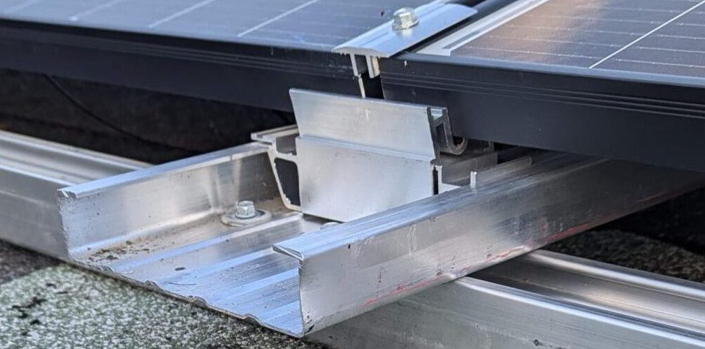 Detailansicht eines Photovoltaik-Montagesystems mit Aluminiumschienen und Modulhalterung auf einem Flachdach